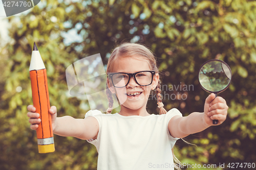 Image of Smiling young child in a uniform standing against a tree in the 