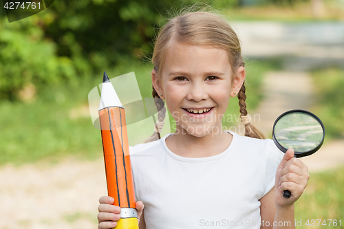 Image of Smiling young child in a uniform standing against a tree in the 