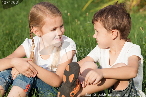 Image of Two happy children playing near the tree on the grass at the day