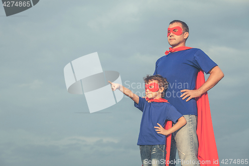 Image of Father and son playing superhero outdoors at the day time.