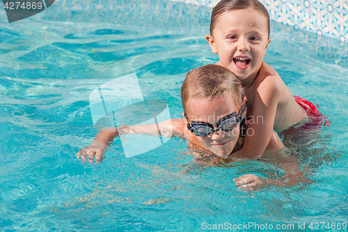 Image of Two happy children playing on the swimming pool at the day time.