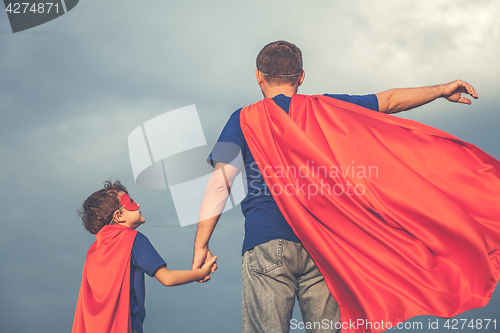 Image of Father and son playing superhero outdoors at the day time.