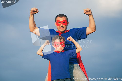 Image of Father and son playing superhero outdoors at the day time.