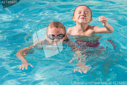 Image of Two happy children playing on the swimming pool at the day time.