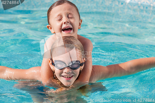 Image of Two happy children playing on the swimming pool at the day time.