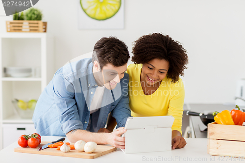 Image of happy couple with tablet pc cooking food at home