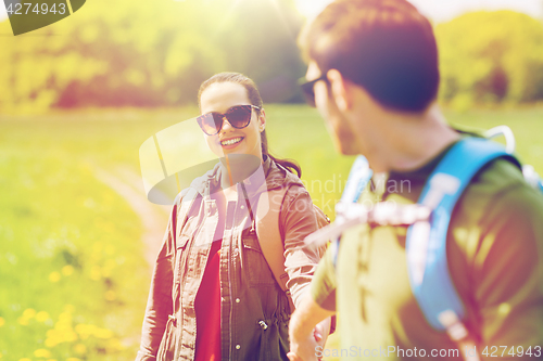 Image of happy couple with backpacks hiking outdoors