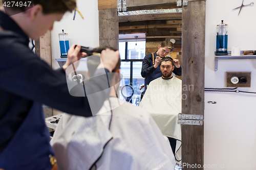 Image of man and barber cutting hair at barbershop