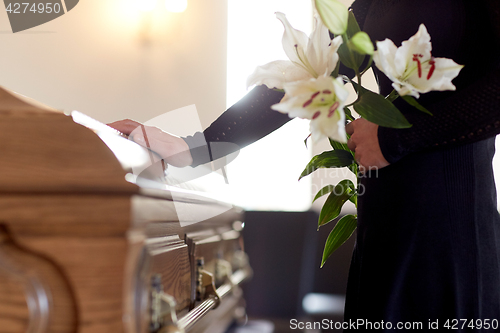 Image of woman with lily flowers and coffin at funeral