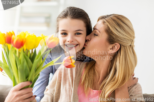 Image of happy girl giving flowers to mother at home