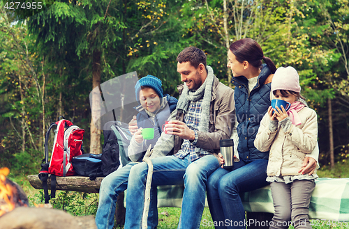 Image of happy family sitting on bench at camp fire