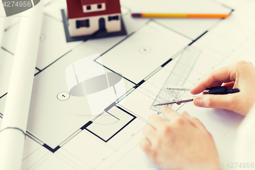 Image of close up of hands with compass measuring blueprint