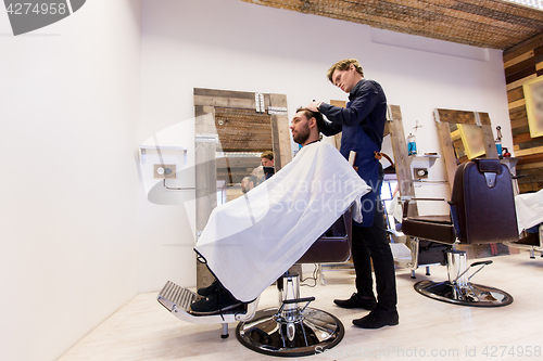 Image of man and barber cutting hair at barbershop