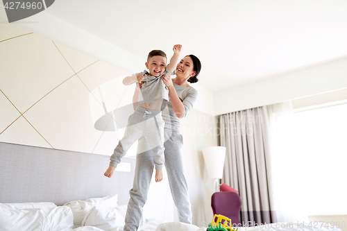 Image of happy mother with son in bed at home or hotel room