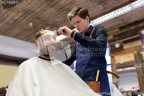 Image of man and barber with trimmer cutting hair at salon