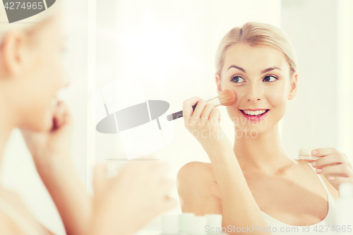 Image of woman with makeup brush and powder at bathroom