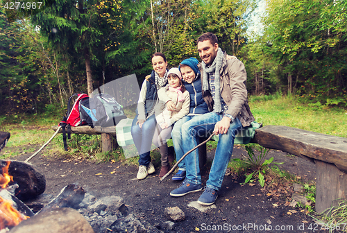 Image of happy family sitting on bench at camp fire