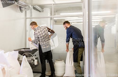 Image of men with malt bags and mill at craft beer brewery