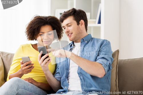 Image of happy couple with smartphones at home