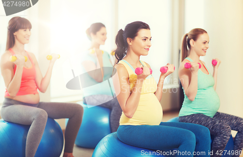 Image of happy pregnant women exercising on fitball in gym