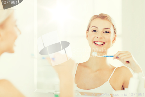 Image of woman with toothbrush cleaning teeth at bathroom