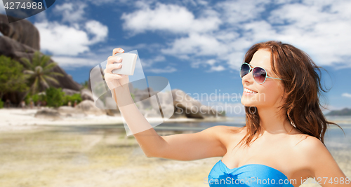 Image of woman in swimsuit taking selfie with smatphone