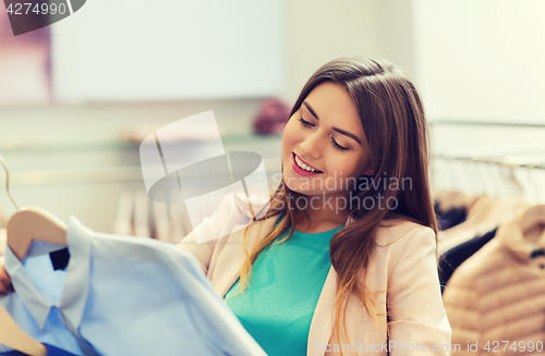 Image of happy young woman choosing clothes in mall