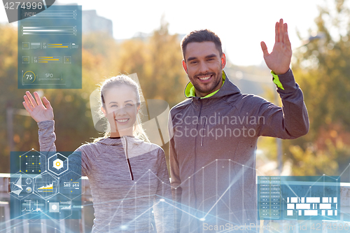 Image of smiling couple waving hand outdoors