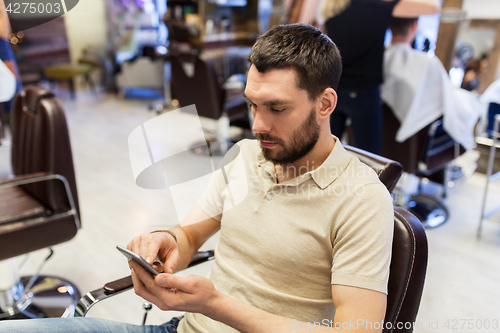 Image of man with smartphone at barbershop or salon