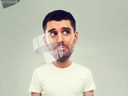 Image of unhappy young man over gray background