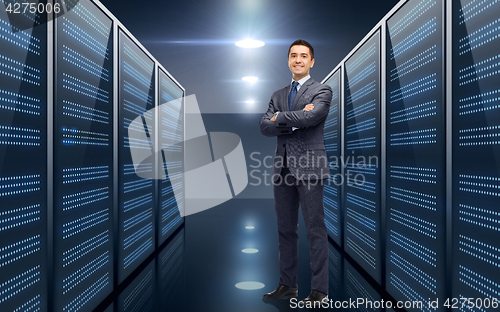 Image of smiling businessman over server room background