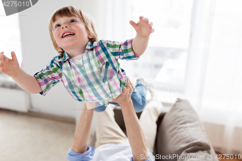 Image of father hands holding happy little boy at home