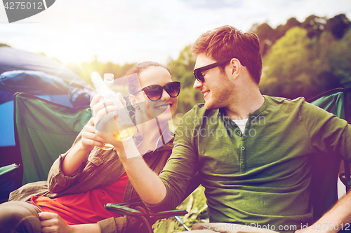 Image of happy couple clinking drinks at campsite tent
