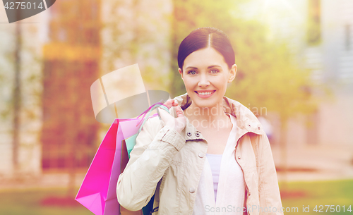 Image of smiling woman with shopping bags coming from sale