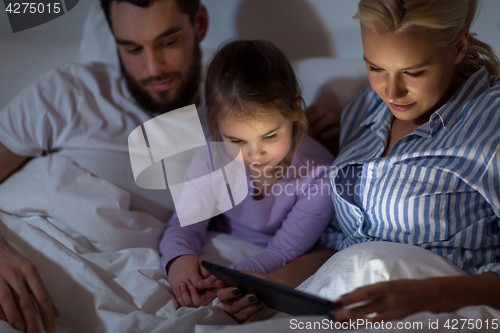 Image of happy family with tablet pc in bed at home