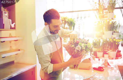 Image of smiling florist man making bunch at flower shop