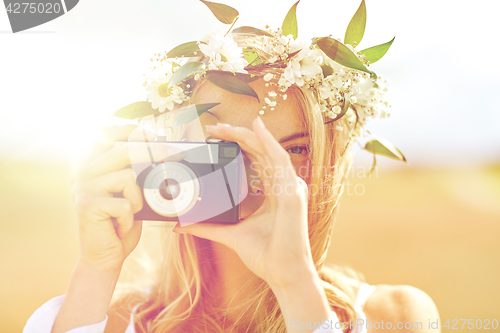 Image of happy woman with film camera in wreath of flowers