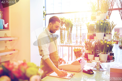 Image of florist man with clipboard at flower shop counter