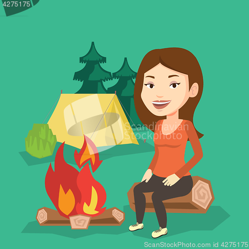 Image of Woman sitting on log near campfire in the camping.