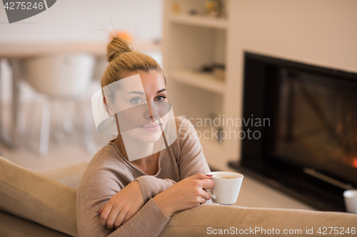 Image of woman with a mug near a fireplace