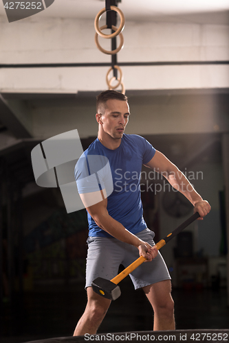 Image of man workout with hammer and tractor tire