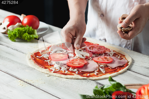 Image of Closeup hand of chef baker in white uniform making pizza at kitchen