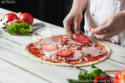 Image of Closeup hand of chef baker in white uniform making pizza at kitchen