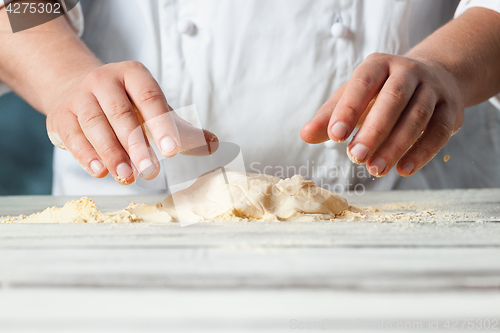 Image of Closeup hand of chef baker in white uniform making pizza at kitchen