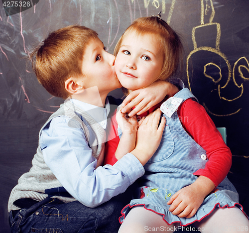 Image of little cute boy kissing blonde girl in classroom at blackboard, first school love, lifestyle people concept 