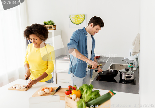 Image of happy couple cooking food at home kitchen