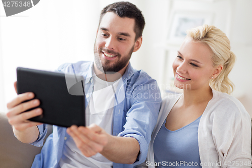 Image of smiling happy couple with tablet pc at home