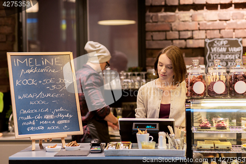 Image of woman bartender at cafe or coffee shop cashbox