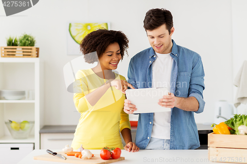 Image of happy couple with tablet pc cooking food at home