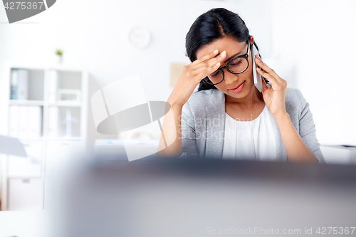 Image of businesswoman calling on smartphone at office